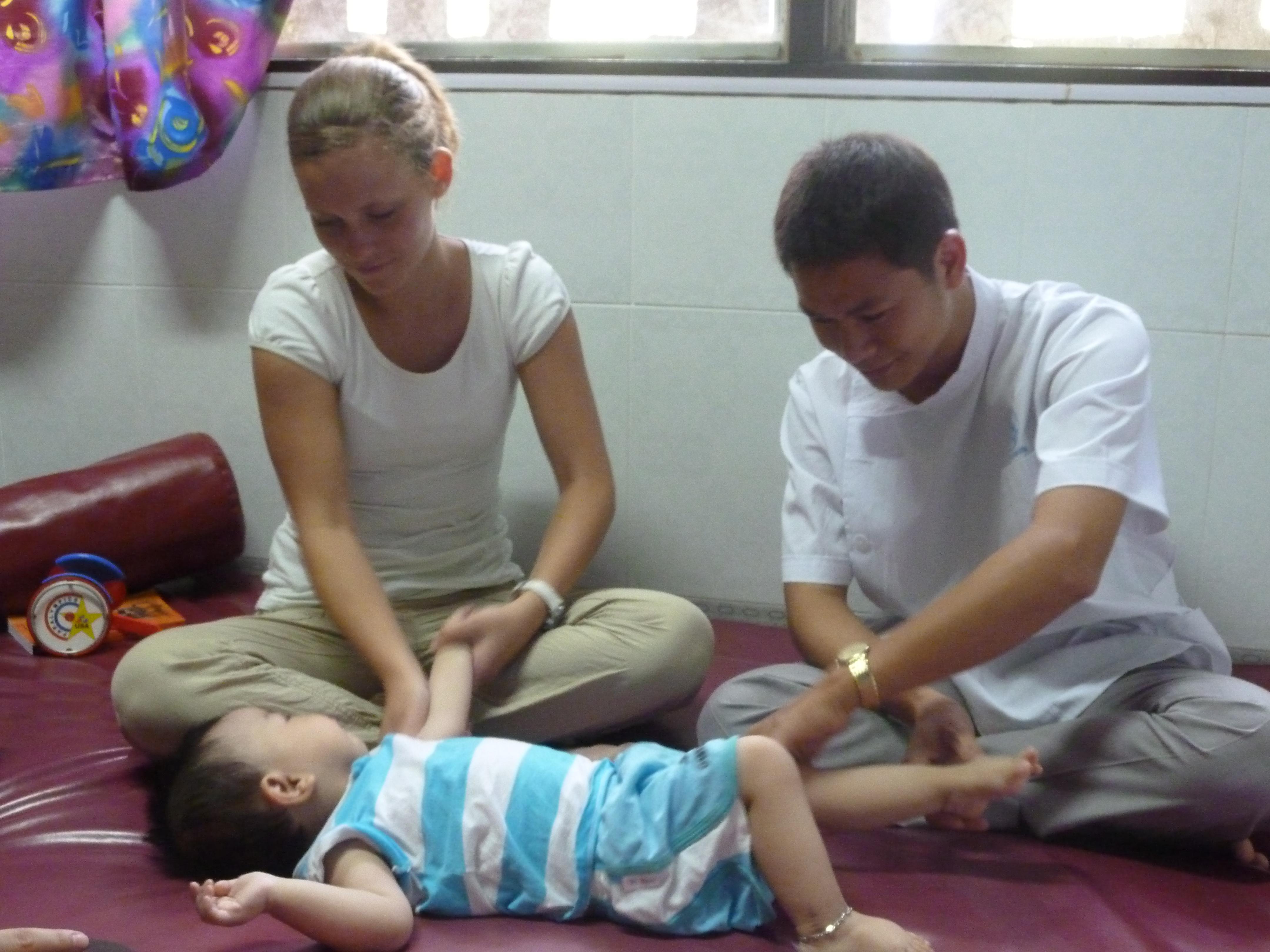 A doctor and female intern from Projects Abroad encouraging movement of a baby during her occupational therapy internship in Vietnam. A female intern is pictured helping a local doctor encourage movement in a baby during her occupational therapy internship in Vietnam.